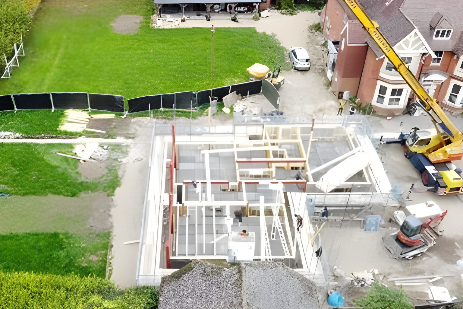 Wide aerial view of the site during construction of the roof structure, with a crane on site