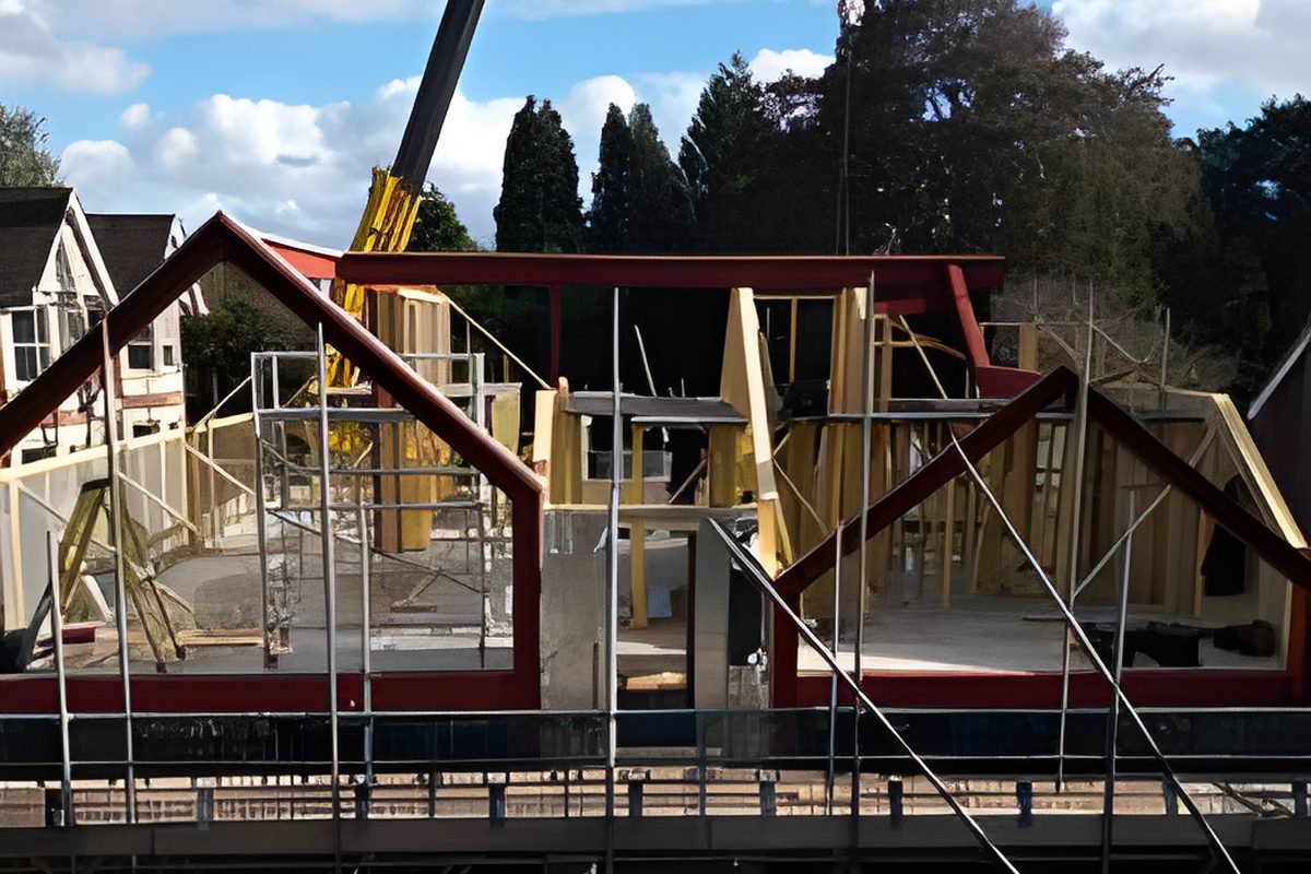 Steel A frames and timber gables on a complex cut roof under construction, with a crane behind