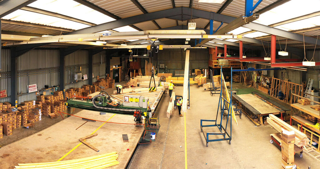 Timber frame manufacturing facility with staff inspecting supplies used for timber frame construction