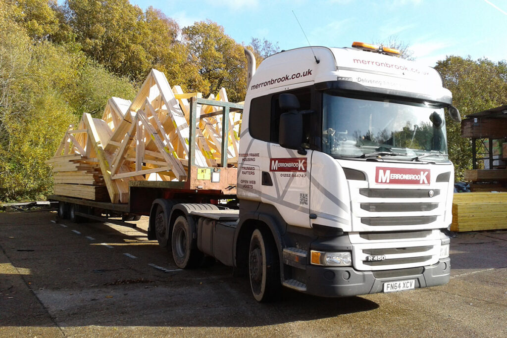 An outdoor scene with Merronbrook branded truck delivering timber frame construction materials