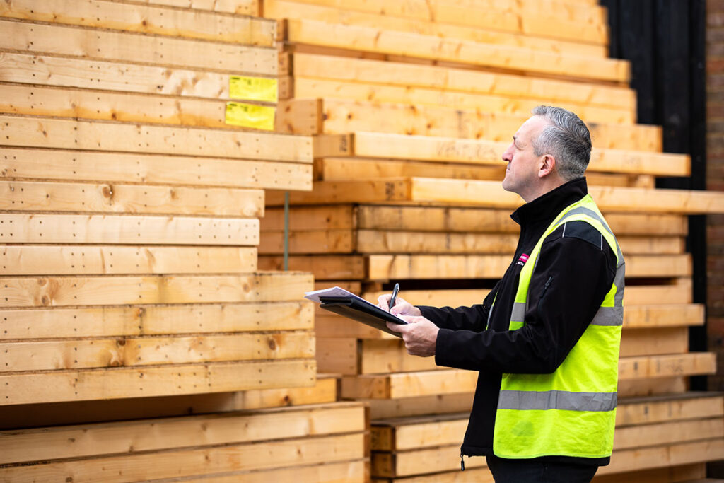 Pallets of materials used in timber frame construction being inspected by a Merronbrook Ltd member of staff